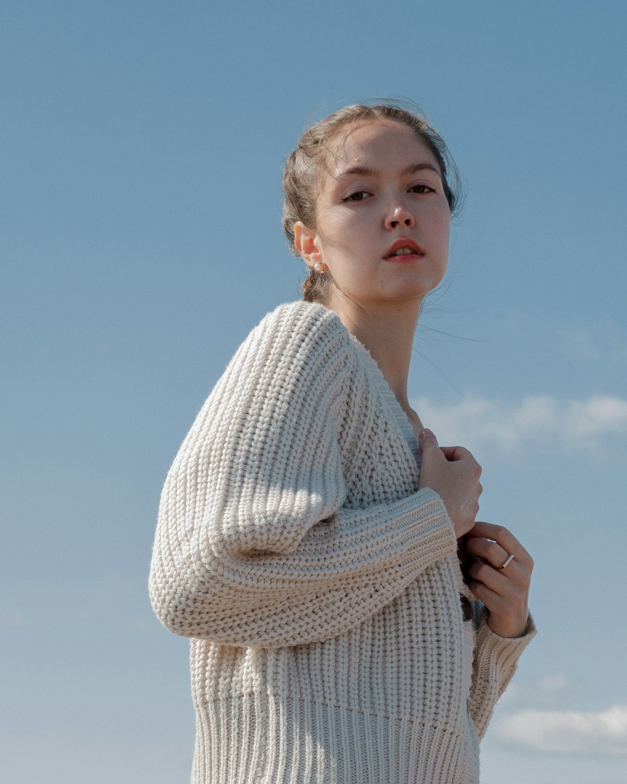 Model in cream knit cardigan against the sky